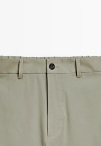 Pantaloni grigi chiari con una vita piatta, chiusura con un solo bottone e passanti per la cintura. Realizzati in tessuto liscio con un taglio sartoriale.