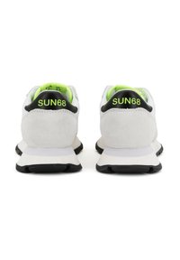 Scarpe sportive grigie e bianche con un accento nero sul tallone e una fodera interna giallo neon. Presentano un logo sul tallone e una suola texturizzata.
