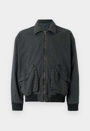 Black bomber jacket with a zip front, two large side pockets, ribbed cuffs, and collar. Made of durable fabric with a smooth texture.