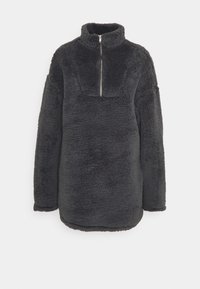 Sudadera de forro polar gris carbón con textura suave, cuello alto, media cremallera frontal y mangas largas. Presenta una superficie texturizada y un ajuste relajado.