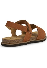 Sandal de ante marrón con suela de corcho, correas entrecruzadas y plantilla acolchada. El diseño incluye cierres ajustables para mayor comodidad.