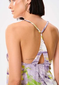 Bloemenprint jurk met paarse en groene tinten, spaghettibandjes, open achterkant ontwerp en een sleutelgat uitsnijding aan de achterkant.