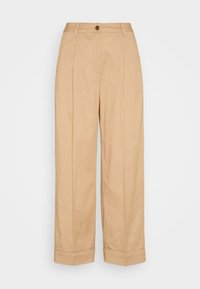 Pantalons larges beige en coton, avec une fermeture à bouton, des plis avant et des revers au bas. Texture lisse.