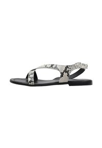 Sandales plates avec un design en imprimé serpent noir et blanc, dotées d'une bride entrecroisée et d'une boucle à la cheville, fabriquées en matériau synthétique texturé.