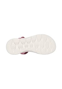 Zapatilla de color rosa claro con una suela de goma blanca texturizada, que presenta un patrón ondulado y una correa de velcro para el cierre.
