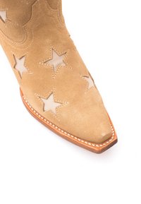 Stivale in suede color nocciola con punta affusolata, caratterizzato da ritagli a stella, cuciture decorative e una suola di un marrone chiaro a contrasto.