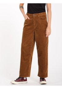 Brune kordfløjlsbukser med lige ben, der har frontlommer og knaplukning. Sammen med maroon højhælede sneakers.