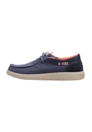 Zapatos slip-on de lona azul marino con suela texturada de color beige, forro interior naranja y pequeños acentos de bandera cerca de los cordones.