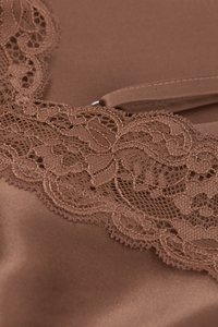 Brunt satinmaterial med invecklade spetsdetaljer längs ena kanten, som framhäver ett blommönster med vågiga kanter.