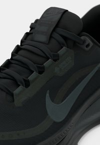 Must have musta Nike jooksujalats, millel on tekstuuriga ülemine osa, tooni sobivad paelad, tugevdatud alad ja nähtav Swoosh-logo tumedamas sinises toonis.