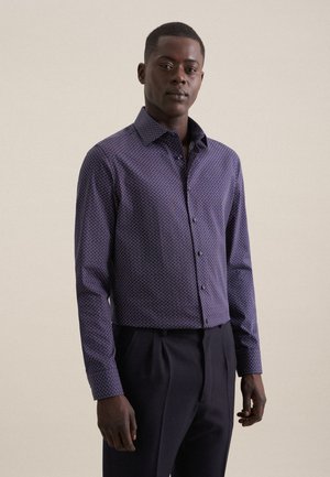 Camicia a bottoni viola con motivo geometrico, con colletto a punta e maniche lunghe, abbinata a pantaloni scuri.