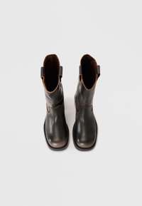 Sorte lær ankle boots med rund tå, med en tan-farget aksent på kanten og trekkfliker på hver side for enkel påkledning. Glatt tekstur.
