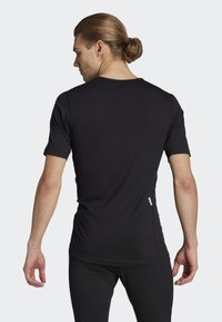 Svart kortärmad t-shirt tillverkad av mjukt material, med en smal passform och en liten etikett på vänster sida nära fållen.