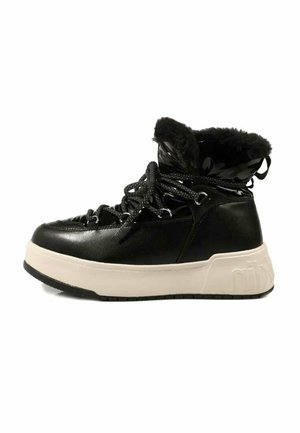 Botas de tobillo sintéticas negras con borde de pelo sintético, suela de goma texturizada y cordones negros. Presentan una plataforma acolchada de color crema.