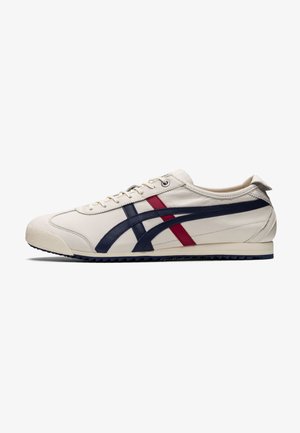 White leather sneaker featuring navy and red stripes, low profile, textured rubber sole, and standard lace-up closure.