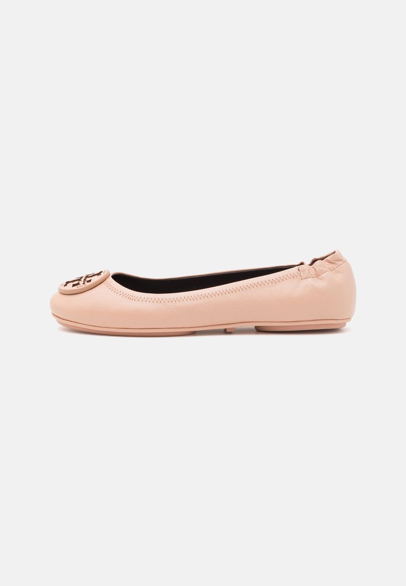Nude-colored leather ballet flats with a rounded toe, stitch detailing, and a logo embellishment on the toe. Soft texture and slip-on design.