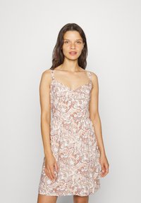 Vestido branco com padrão paisley em tons de ferrugem e castanho, com alças finas e uma cintura ajustada que se alarga na bainha.