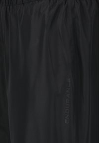 Sorte letvægts shorts med elastisk talje, der har en tekstureret overflade og et reflekterende "ENDURANCE" logo på siden.