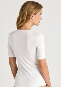 Witte slim-fit top gemaakt van een gladde, rekbare stof. Beschikt over korte mouwen en een ronde halslijn, met een naadloos ontwerp aan de achterkant.