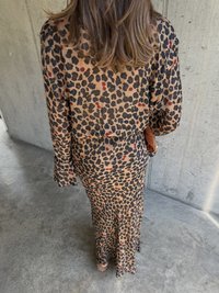 Sukienka w wzór panterki z długimi rękawami, dopasowanym kroju i lekko rozszerzającym się dołem. Kolory to brąz, czerń oraz akcenty w kolorze czerwonym.