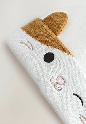 Valkoinen neulottu hattu, jossa on ruskea eläinvaatteiden muotoilu, ja siinä on brodeerattuja yksityiskohtia, kuten musta silmä ja vaaleanpunainen nenä, pehmeä rakenne.