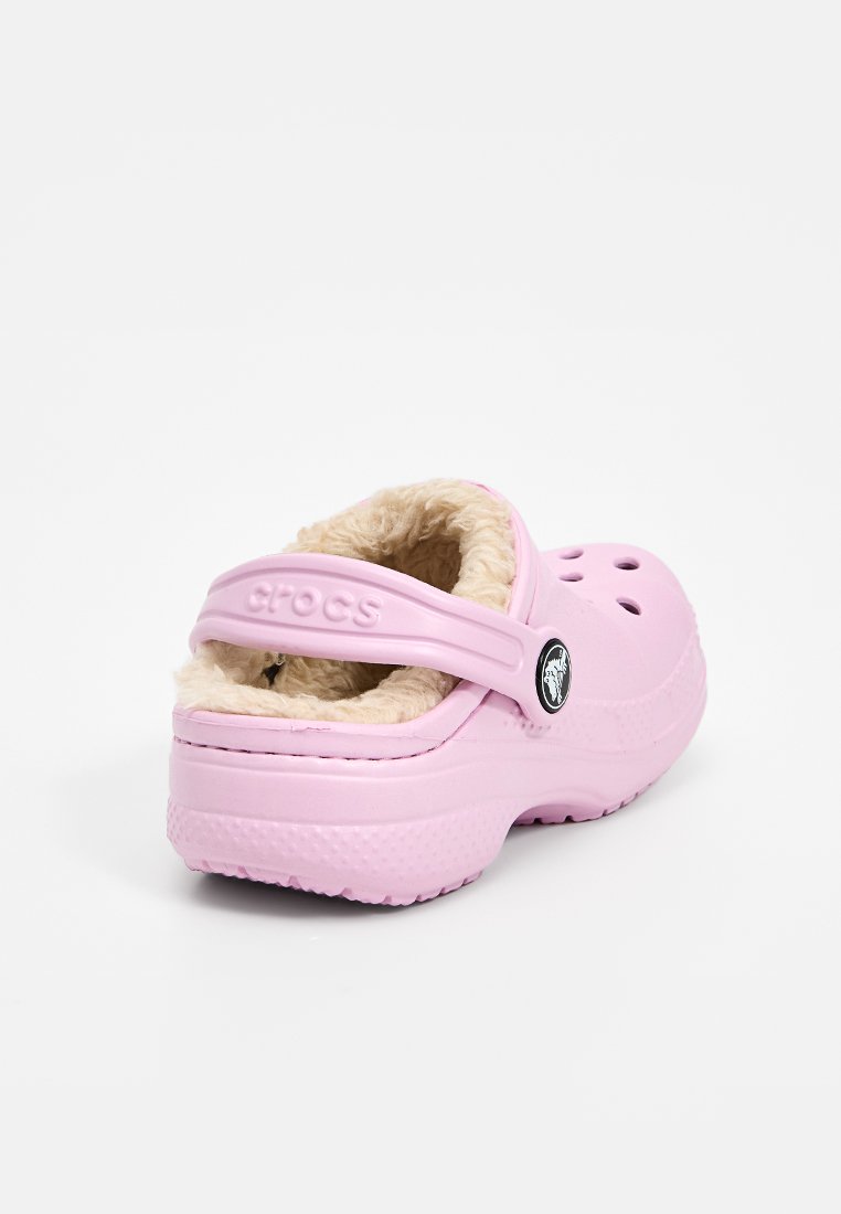 Zoccolo in gomma rosa con cinturino, dotato di una morbida fodera in pile color crema e fori di ventilazione sui lati.