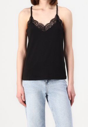 Camicetta nera con spalline sottili, caratterizzata da un bordo in pizzo lungo il scollo. Tessuto liscio, vestibilità casual, abbinata a jeans di denim blu chiaro.
