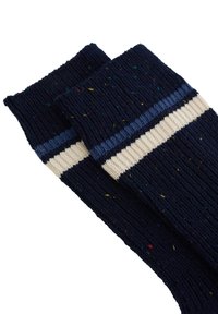 Tamsiai mėlynos megztos kojinės su pakaitiniais kreminiu ir šviesiai mėlynos juostomis, turinčios daugiaspalvių dėmėlių visame audinyje.