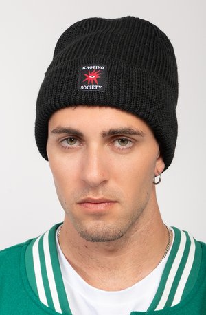 Schwarze Strickmütze mit gerippter Struktur, versehen mit einem rechteckigen Patch mit roter und schwarzer Schrift "KAOTIKO" und "SOCIETY."