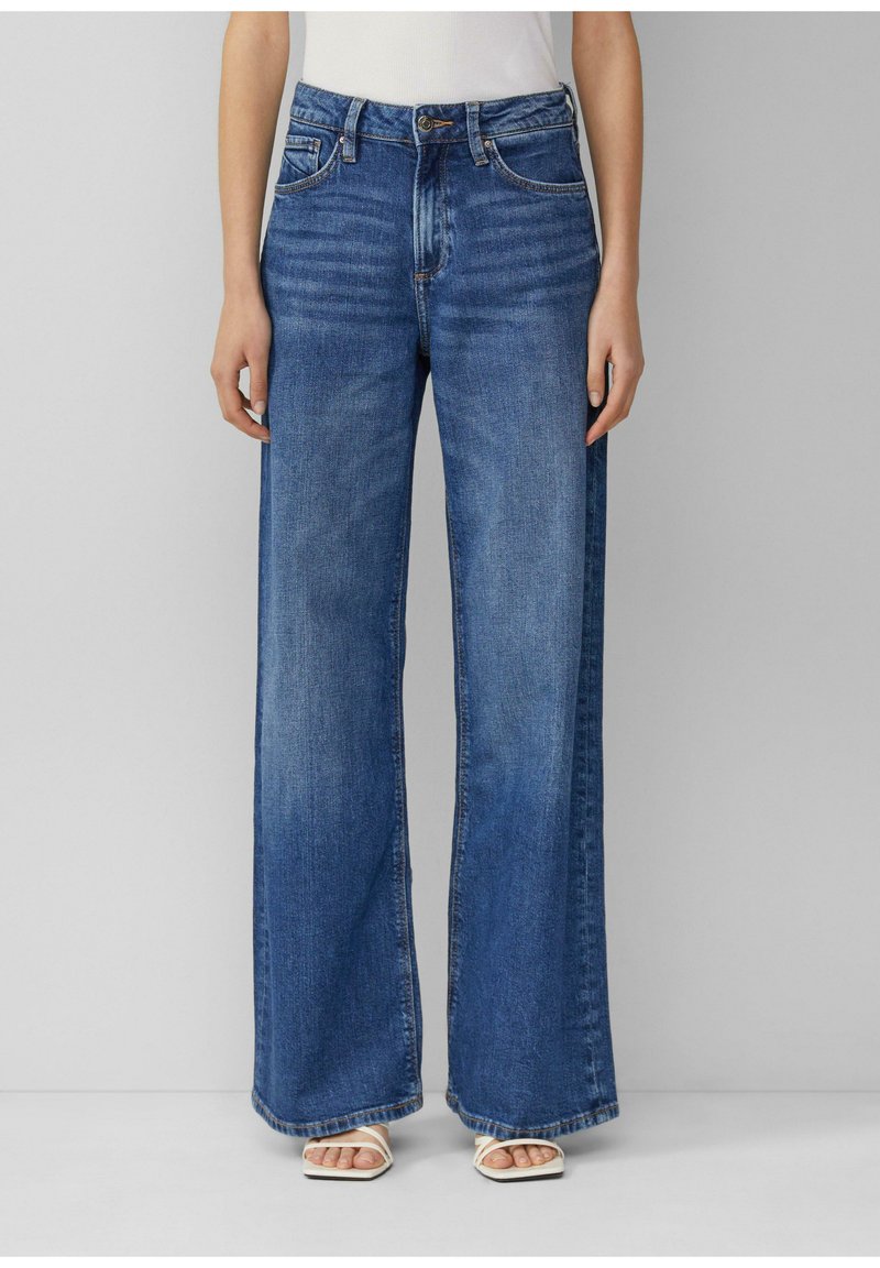 Jean en denim à jambes larges dans un bleu moyen, avec une taille haute, cinq poches, un léger délavage et un ourlet net.