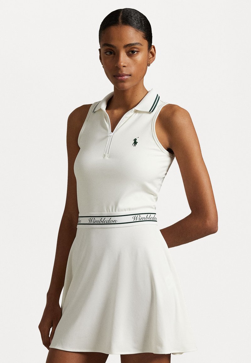 Weißes ärmelloses Polokleid mit Kragen, grünen Akzenten und einem "Wimbledon"-Bund. Hergestellt aus glattem, leichtem Stoff.