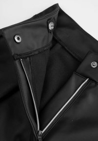 Wnętrze czarnej kurtki z sztucznej skóry z kieszenią na zamek błyskawiczny i zapięciem na napy. Posiada gładką teksturę i kontrastowe podszycie.