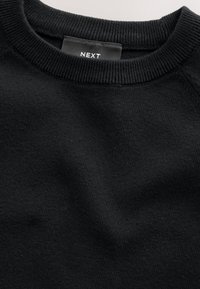 Sweat-shirt en maille noire avec un col rond côtelé et une étiquette cousue à l'intérieur portant la mention « NEXT ». Texture douce et coupe standard.