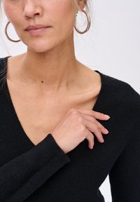 Czarny żebrowany sweter z dekoltem w kształcie litery V, długimi rękawami i dopasowanym krojem. Zauważalnym szczegółem jest miękka tekstura i minimalistyczny design.