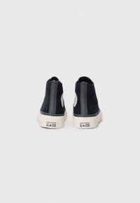 Sneaker alte nere con tomaia in tela, accenti grigi a contrasto e suola in gomma bianca. Presentano il logo iconico sul lato e il tallone personalizzato.