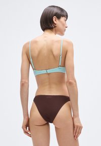 Set de bikini format dintr-un sutien turcoaz texturat cu bretele subțiri și o parte de jos maro ciocolatiu cu model tip ripă, conceput pentru un aspect minimalist.