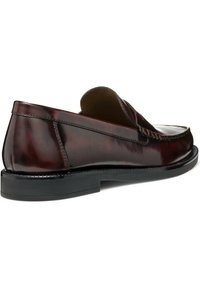 Mocassins en cuir marron sans lacets avec une finition lisse, des coutures décoratives et une semelle en caoutchouc noir basse. Design minimaliste avec bout arrondi.