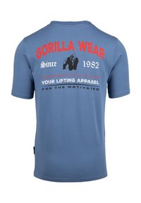 Blauwe katoenen T-shirt met rode en witte tekst op de achterkant, een logo van een gorilla en een relaxte pasvorm met korte mouwen.
