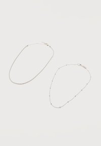 Δύο λεπτά βραχιόλια αλυσίδας από ασήμι με κούμπωμα καβουράκι· το ένα με μικρές στρογγυλές χάντρες τοποθετημένες ομοιόμορφα κατά μήκος της αλυσίδας.