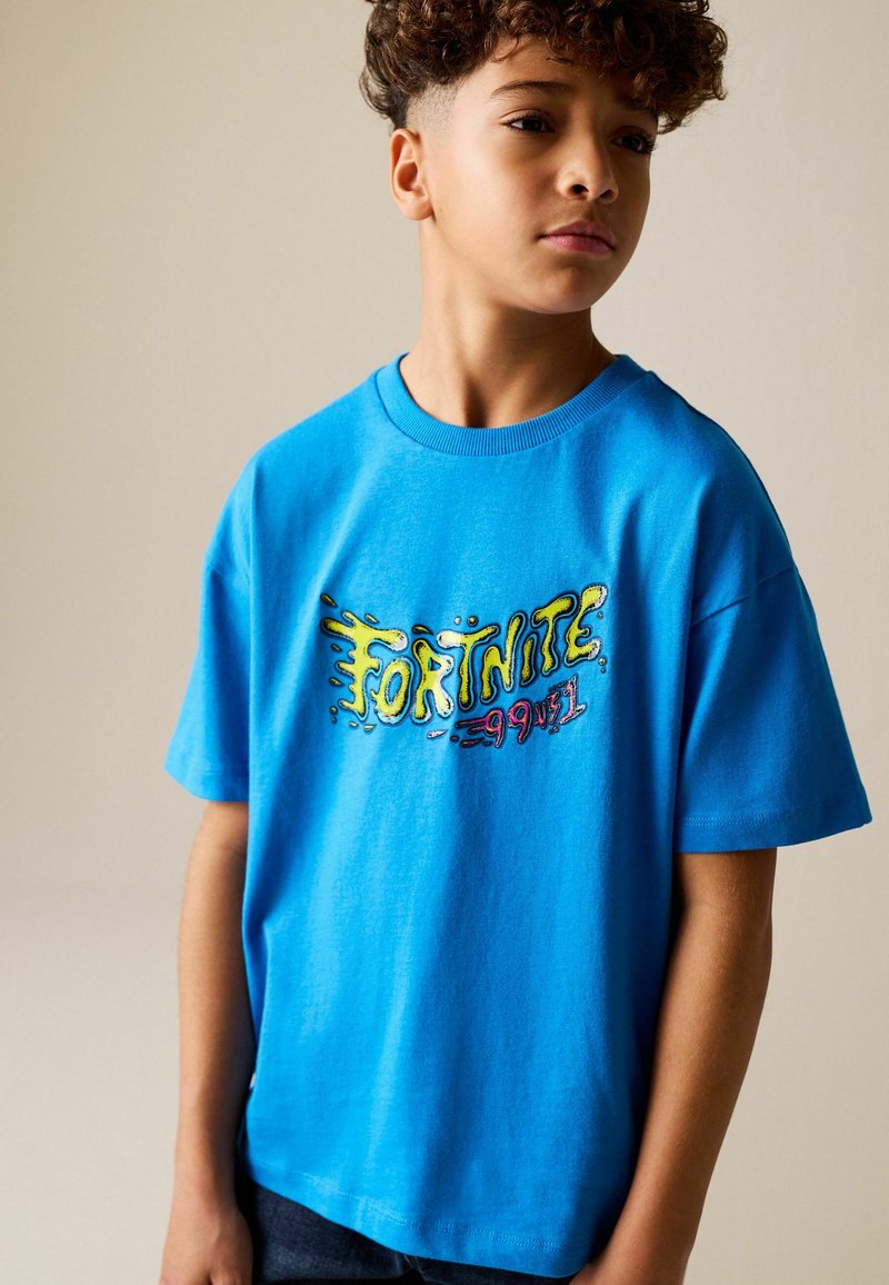 T-shirt en coton bleu avec le logo "FORTNITE" en design graphique coloré sur le devant. Manches courtes et encolure ronde.
