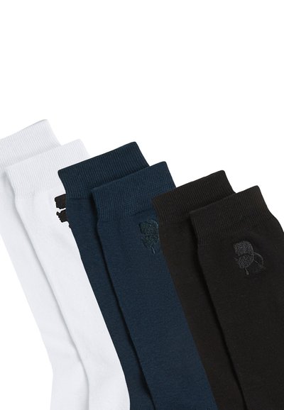 Quatre paires de chaussettes en coton : blanches, bleu foncé et noires. Chaque paire présente un motif texturé et un petit logo sur la cheville.