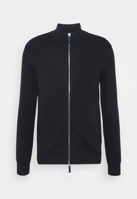 Svart stickad zip-up kofta med hög krage, ribbade ärmslut och nederkant; har en silverfärgad dragkedja och en liten logotyp på bröstet.