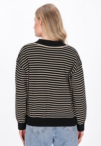 Pullover a righe nere e beige, con scollatura rotonda, polsini a coste e vestibilità morbida. Realizzato in morbido materiale knit, superficie testurizzata.