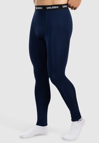 Mörkblå leggings tillverkade av ett mjukt, stretchigt tyg, med en svart midja där varumärket står i vitt. Åtsittande design, utan mönster.