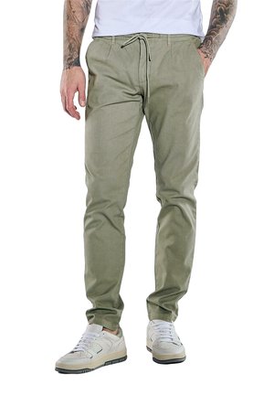 Light olive green trousers with a drawstring waist, slim fit, and smooth texture, paired with white sneakers.
