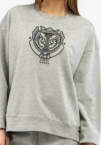 Gray oversized sweatshirt made of soft fabric featuring a black graphic with a crown, wings, and text "ICE" at the center.