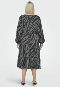 Pitkähihainen, kerroksittainen mekko harmaana mustalla seepra-kuviolla. Sisältää avara selkäyksityiskohta ja pehmeä kangastrap.