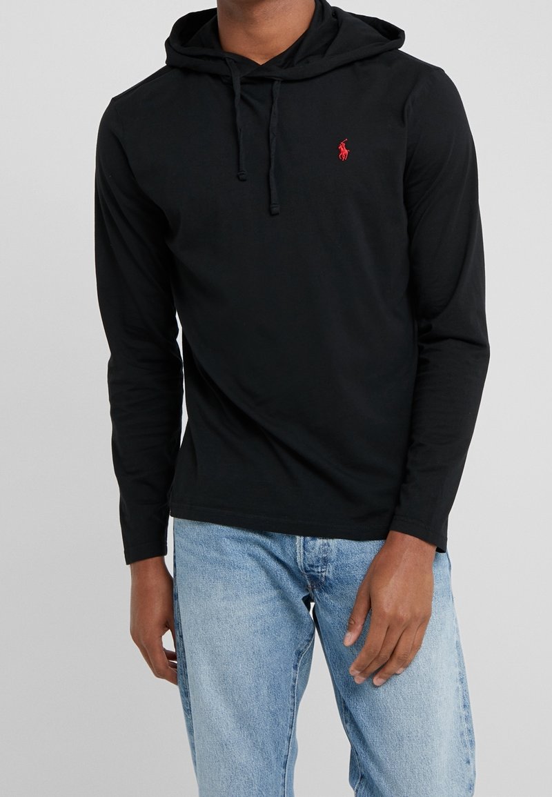 Svart långärmad hoodie med en framficka, snören och en liten röd logga på vänster bröst. Slät bomullstyg.