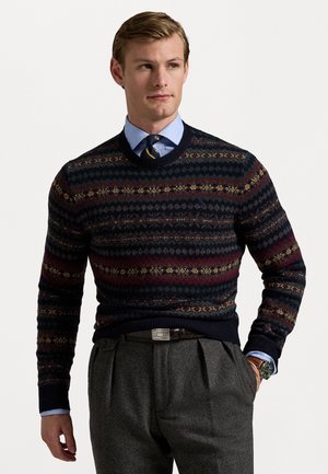 Navy blue knit sweater with multicolored fair isle pattern, featuring shades of burgundy, green, and gold, paired with gray pleated trousers.