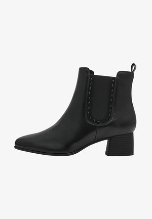 Bottines noires en cuir lisse avec des panneaux élastiques sur les côtés et des clous décoratifs. Dotées d'un talon bloc épais et d'un design à bout pointu.